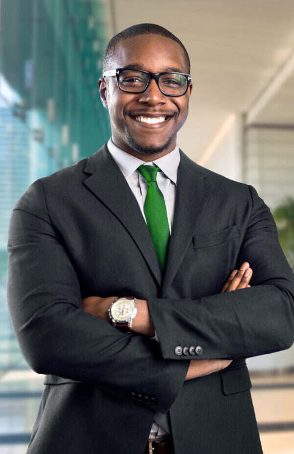 A black executive in a suit standing with his arms crossed